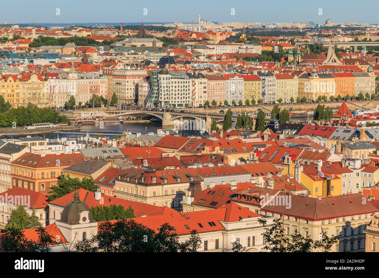 View over the roofs of Prague from the Mala Strana viewpoint with the Vltava river and roads, bridge and house on the shore in sunny day and blue sky Stock Photo