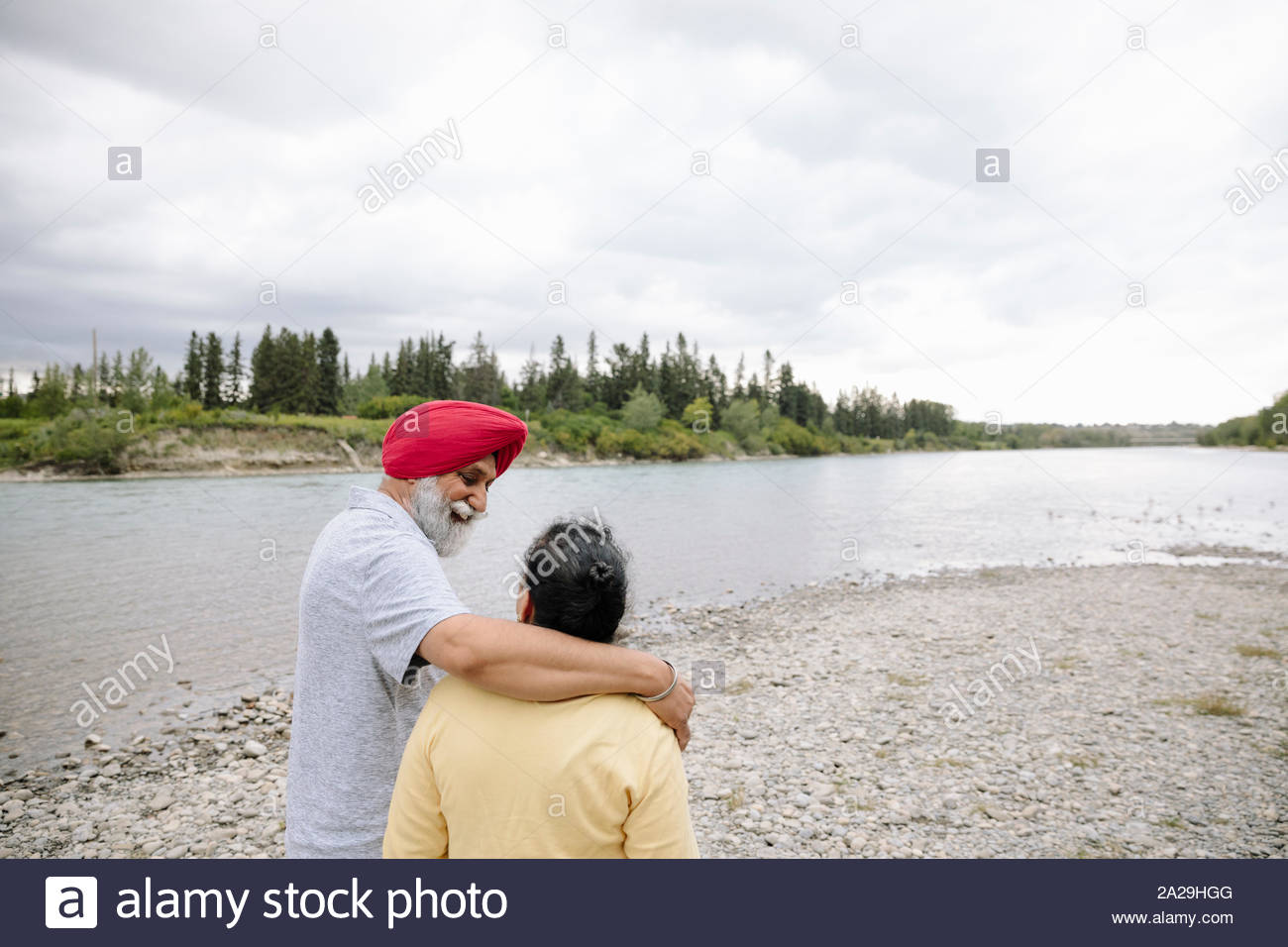 Mature man with arm around senior woman on lakeshore Stock Photo