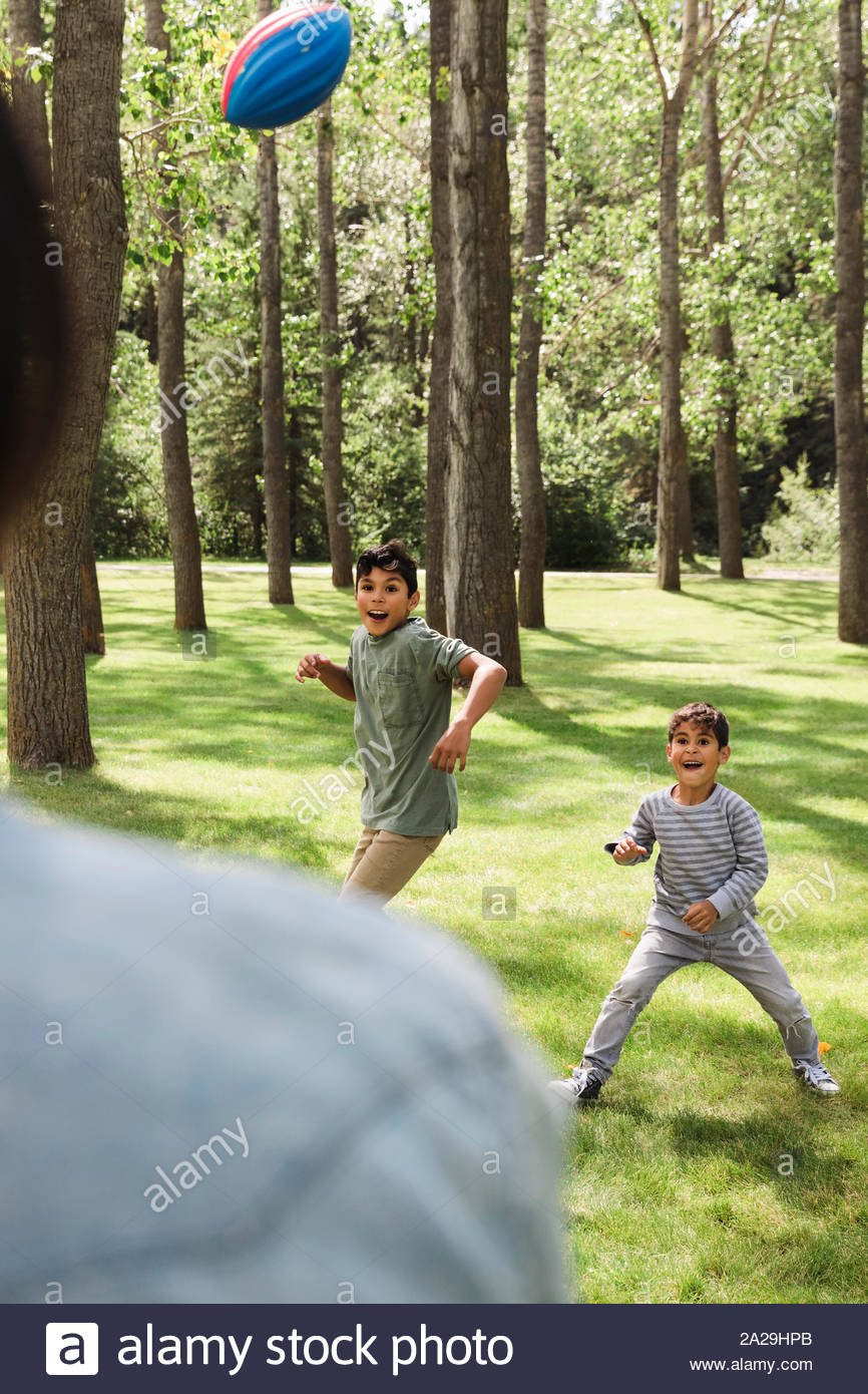 Brothers playing ball with father in urban park Stock Photo Alamy