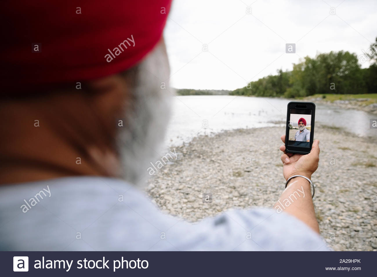 Indian man taking selfie on lakeshore Stock Photo