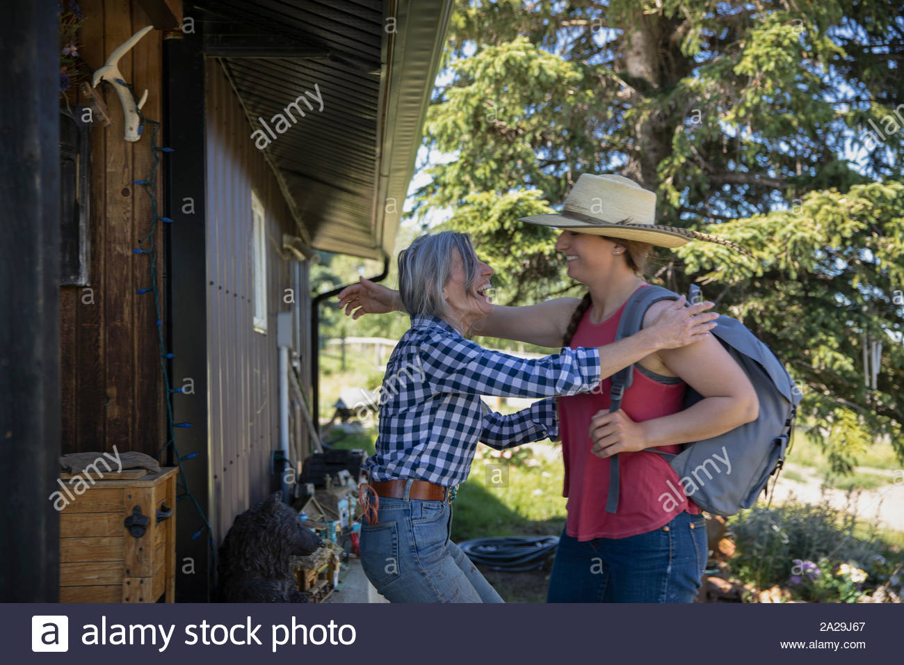 Daughter arriving home to ranch and hugging mother Stock Photo