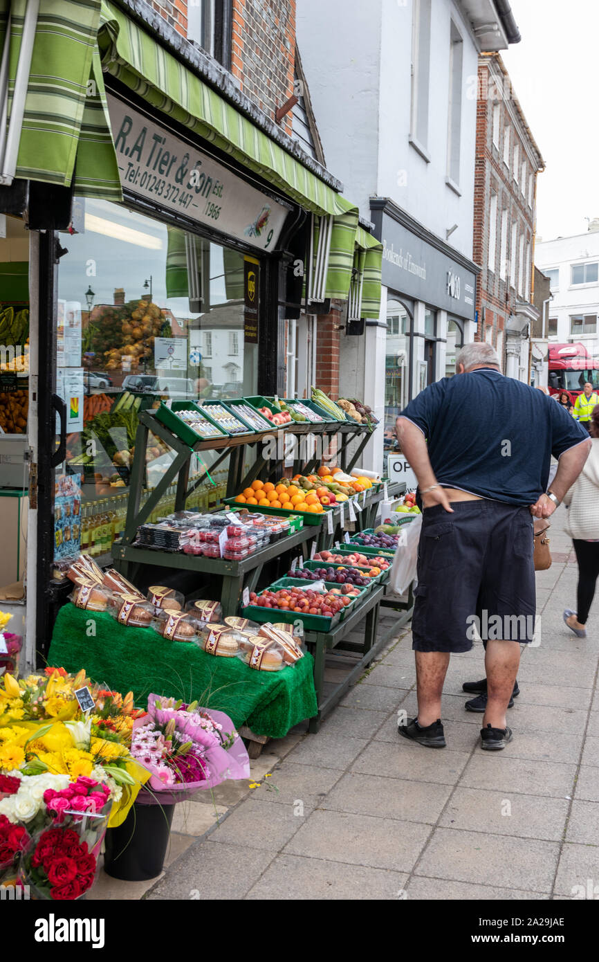 People looking at fruit and vegetables on the stand of a tradition greengrocers in an English village Stock Photo