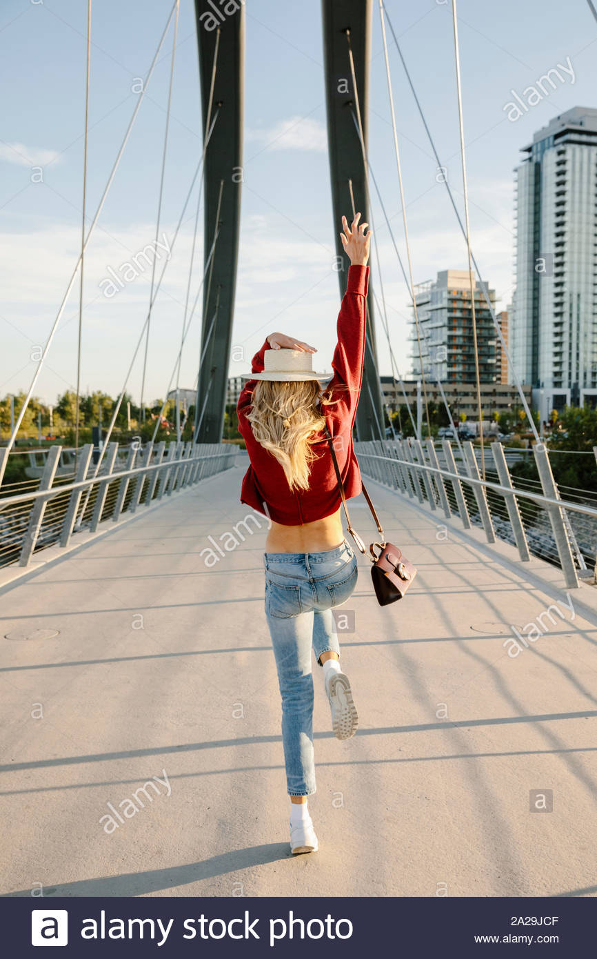 Playful young woman on sunny, urban bridge Stock Photo