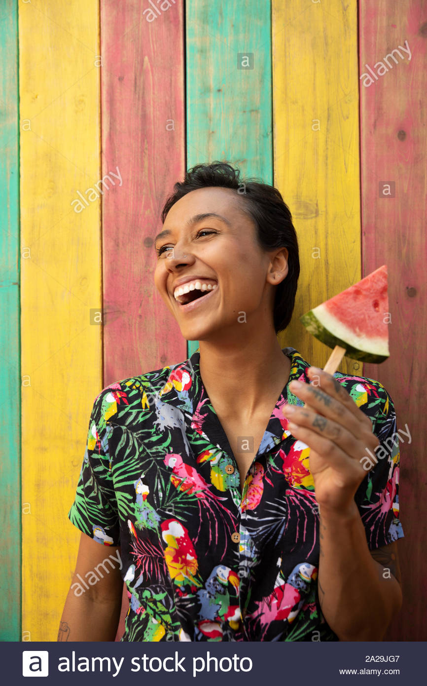 Portrait carefree young woman eating watermelon slice on summer patio Stock Photo