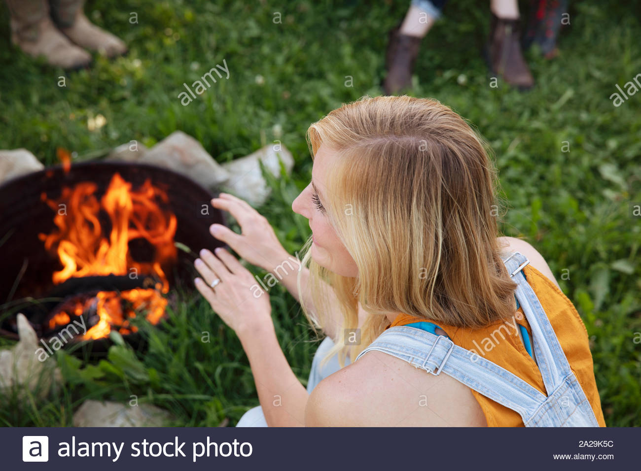 High angle of young woman warming hands by campfire Stock Photo