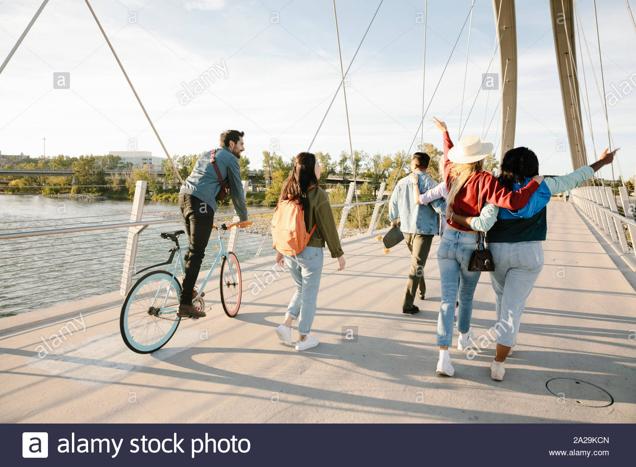 Playful young adult friends on sunny, urban footbridge Stock Photo