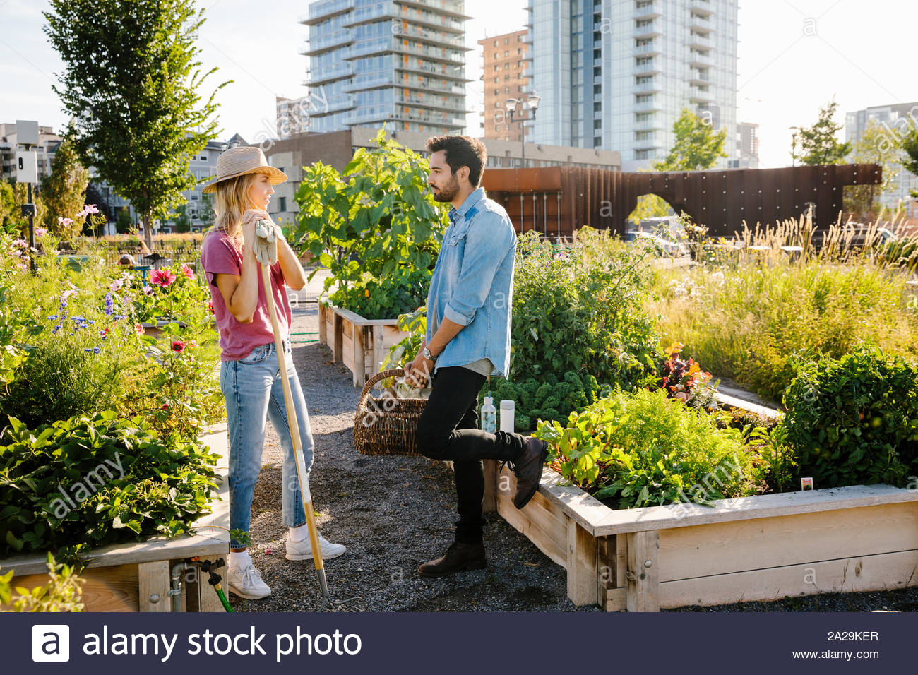 Young couple talking in sunny, urban community garden Stock Photo