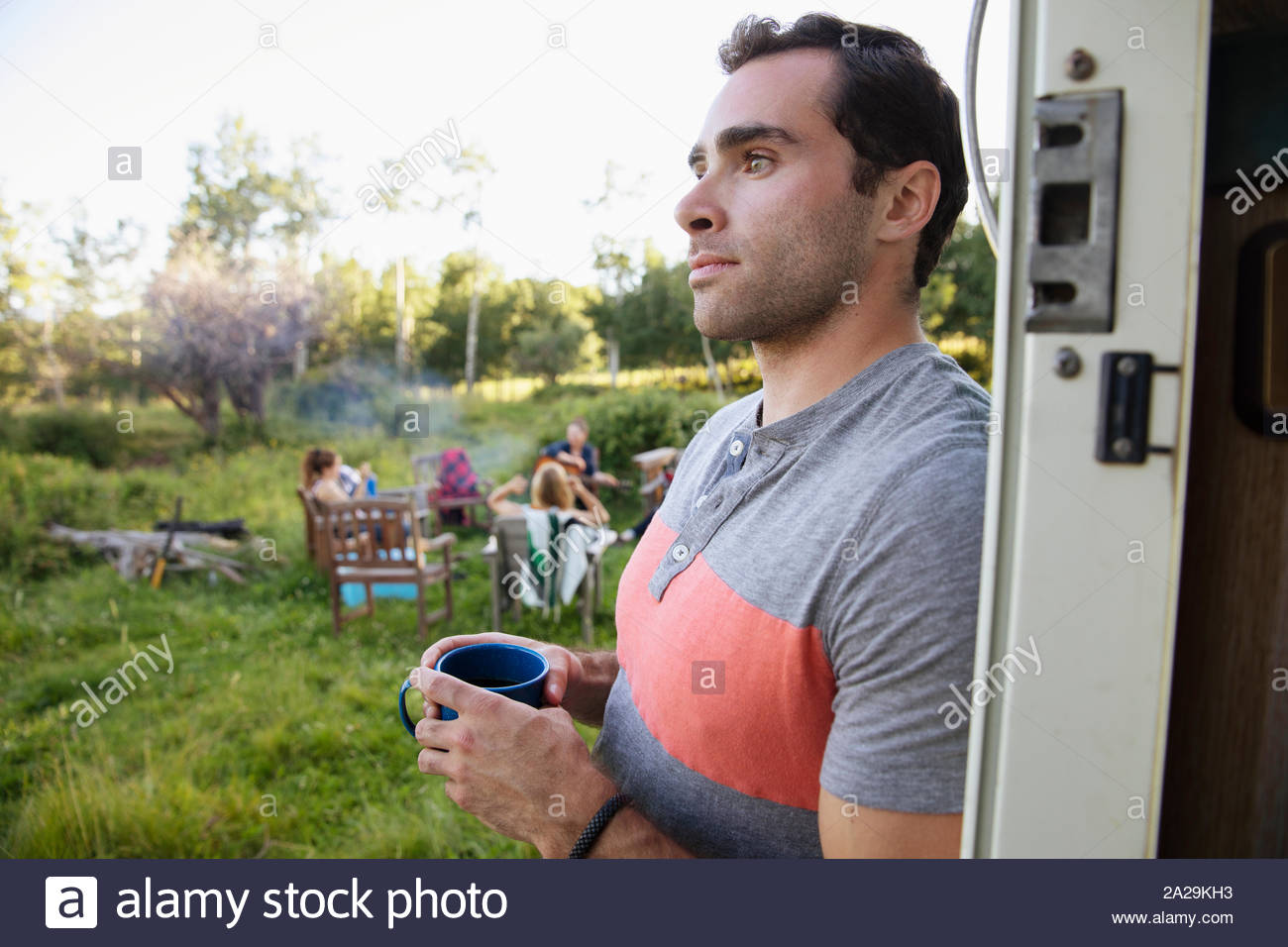 Young man with coffee outside motorhome Stock Photo