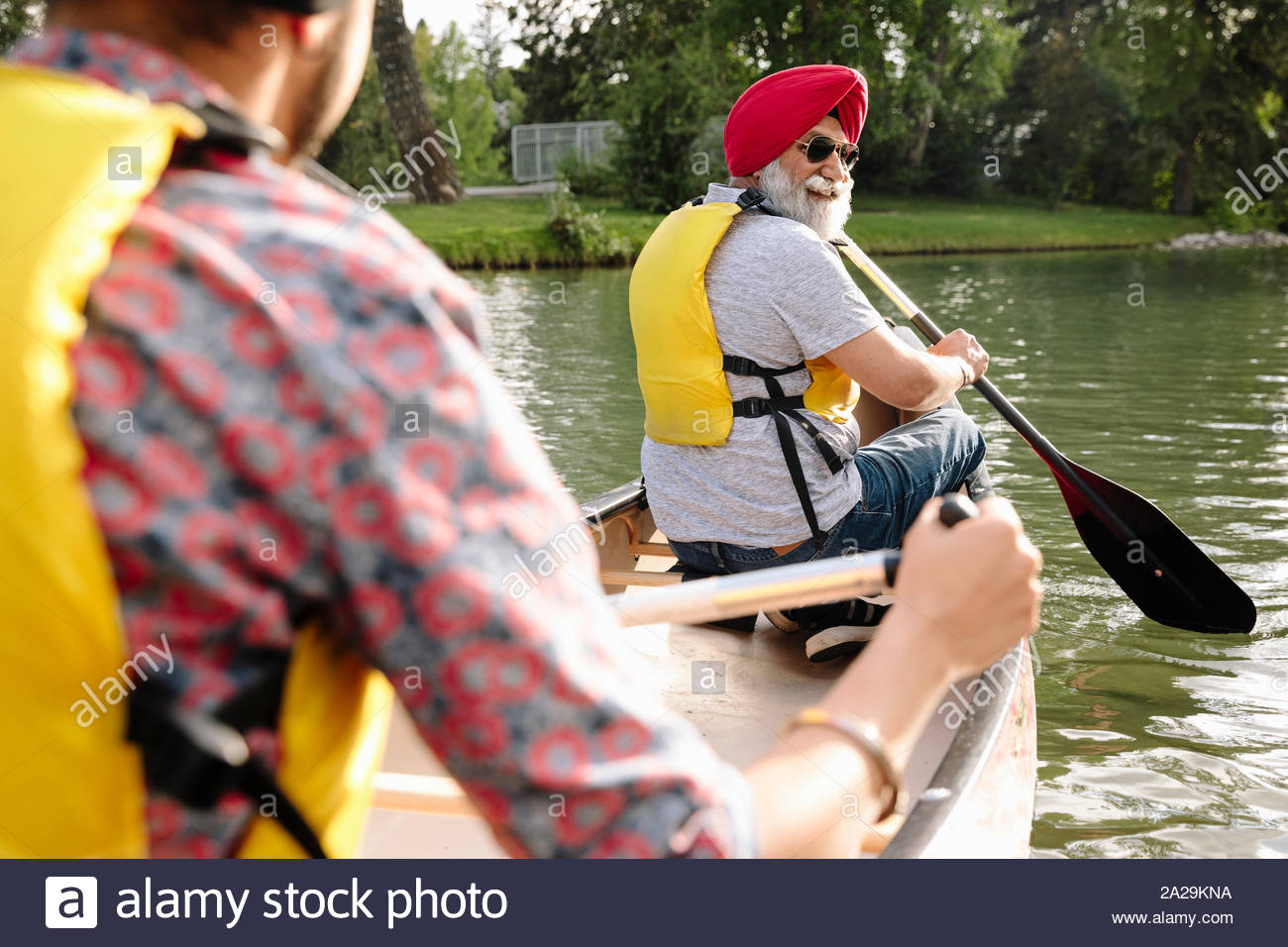 Mature Indian man canoeing and looking over shoulder Stock Photo