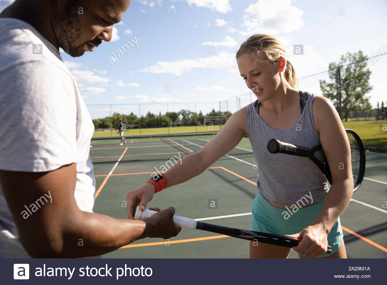 Young woman teaching man how to grip tennis racket on sunny tennis racket Stock Photo