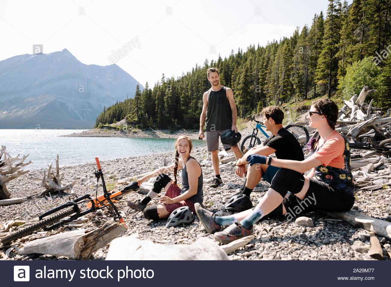 Friends relaxing, taking a break from mountain biking at sunny lakeside Stock Photo