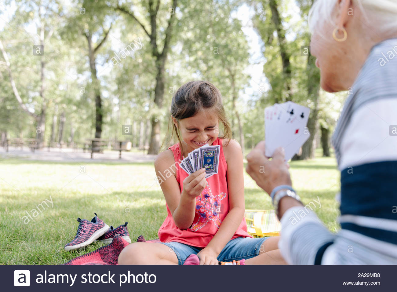 Granddaughter and grandmother playing cards in park Stock Photo