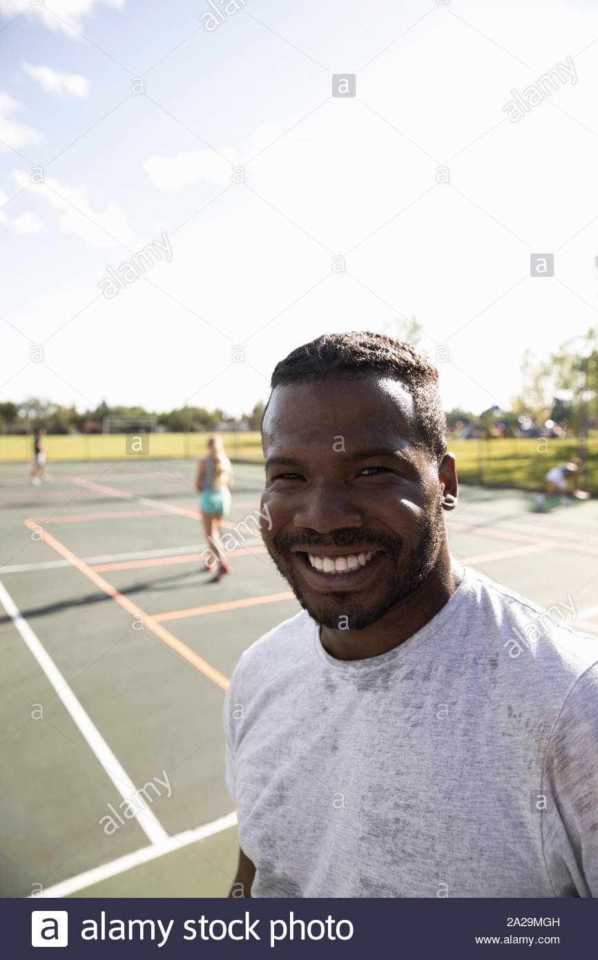 Portrait happy, confident man on sunny tennis court Stock Photo