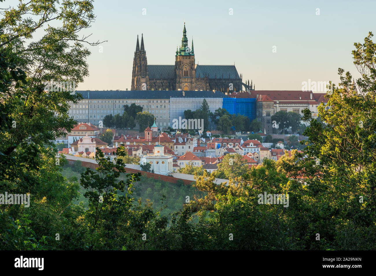 View of Prague Castle with the St. Vitus Cathedral from the viewpoint Petrin in the Mala Strana district on sunny day with blue sky trees and bushes i Stock Photo