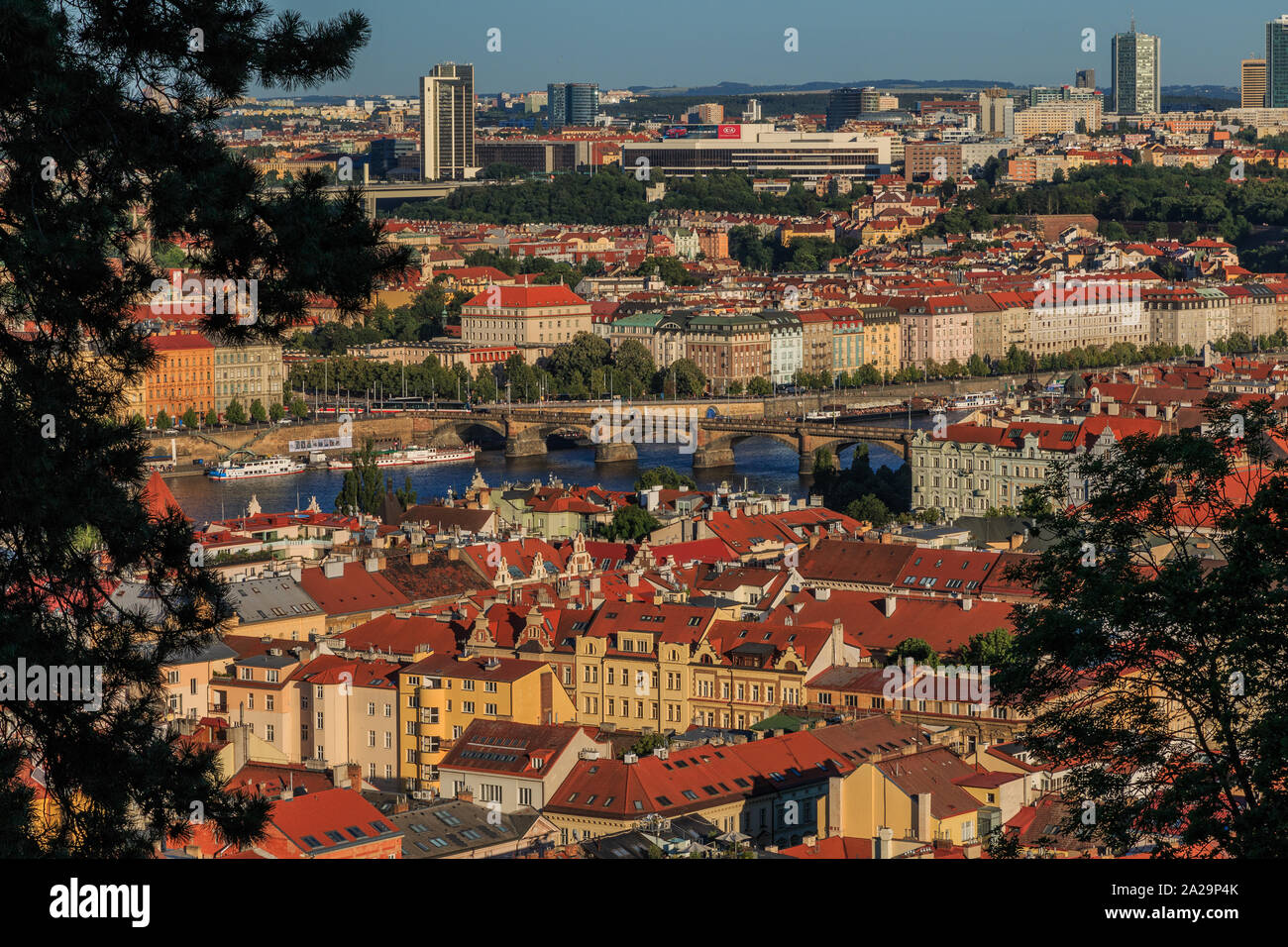 View from the Petrin hill viewpoint over the rooftops of Prague in the district of Mala Strana with the Vltava and road, bridge and house on the shore Stock Photo