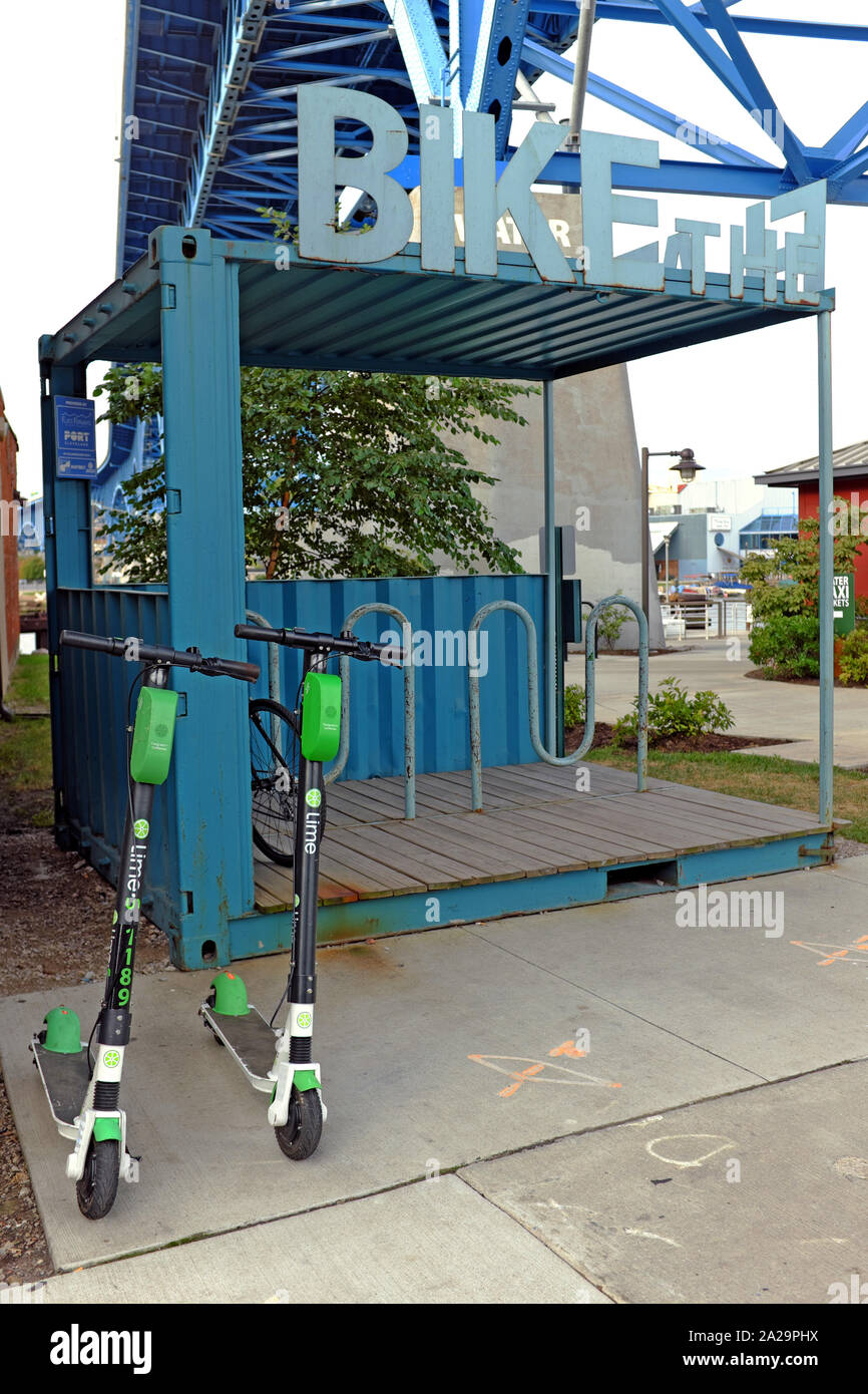 A bike rack stands empty on the East Bank of the Flats in Cleveland, Ohio while two Lime scooters are parked in front. Stock Photo