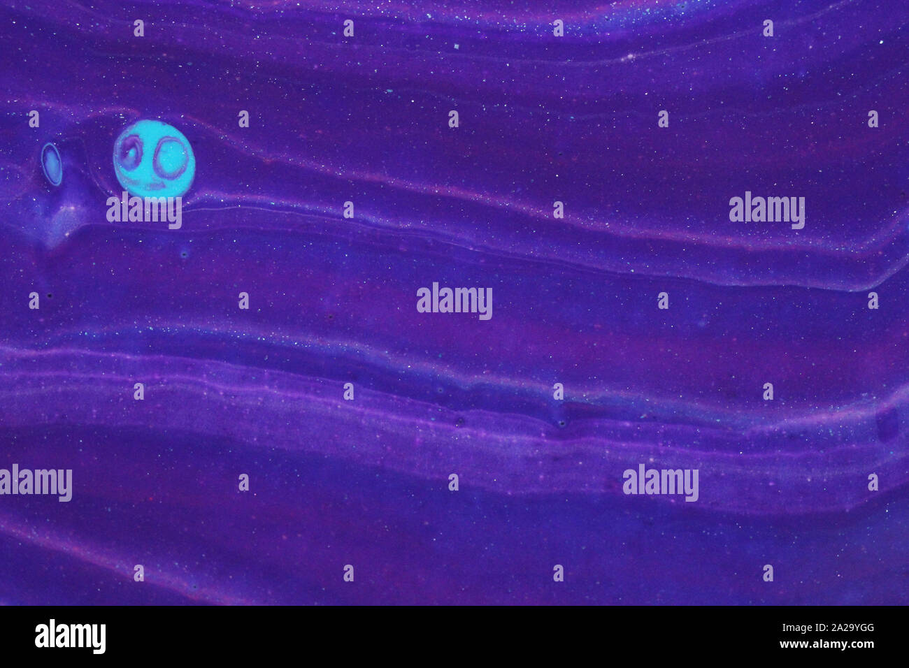 A smiley blue moon is hanging out in a creepy purple Halloween sky with wispy cloud layers for backgrounds. Stock Photo