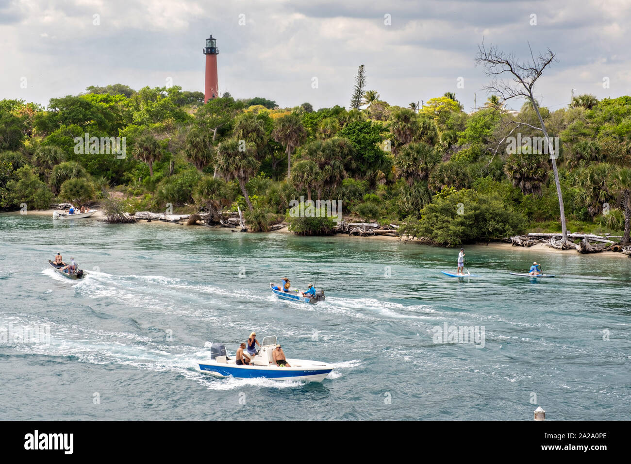Paddle boarders and boats travel along the Indian River past the
