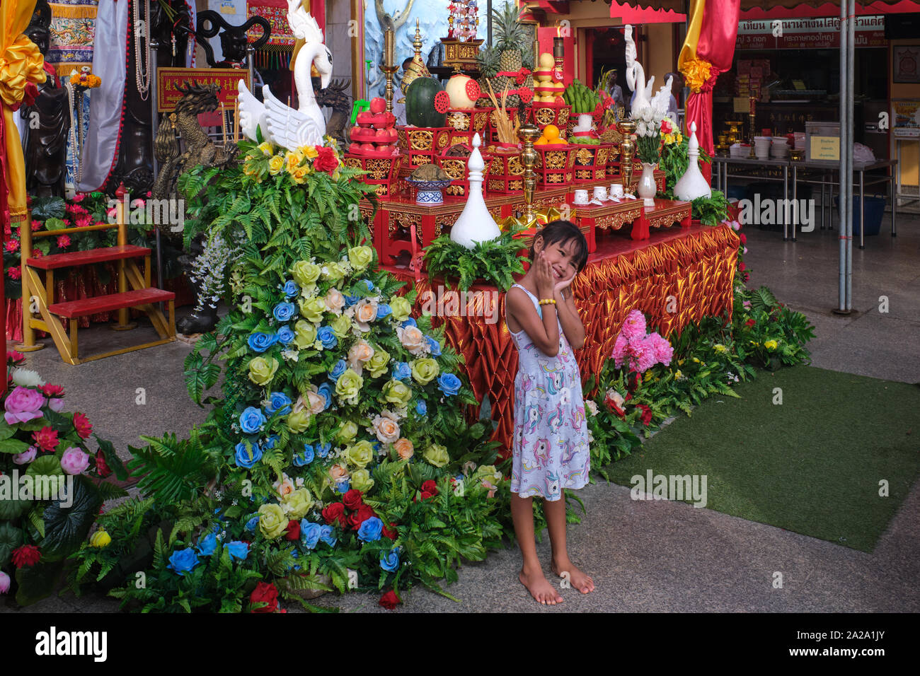 A girl poses in front of a shrine in Pud Jor Temple, a Chinese temple in Phuket Town, Phuket, Thailand Stock Photo
