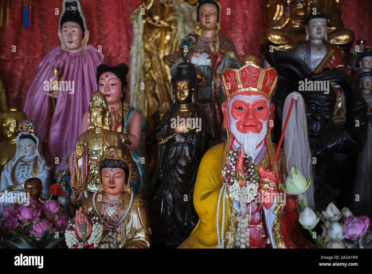 A statue of the Chinese Monkey King or Sun Wukong surrounded by other   mythological figures, at a shrine in Pud Jor Temple, Phuket Town, Thailand Stock Photo