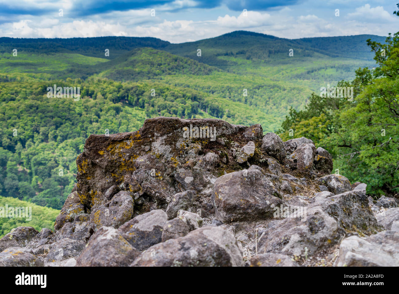 Rocks on a tree covered mountain and cloudy sky Stock Photo