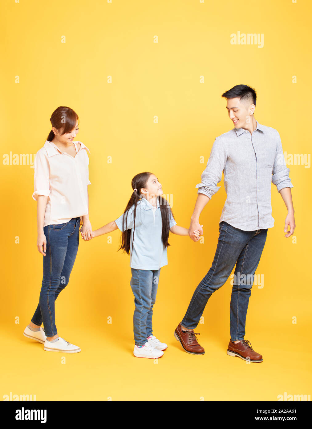 Full length portrait of happy family walking over yellow background Stock Photo