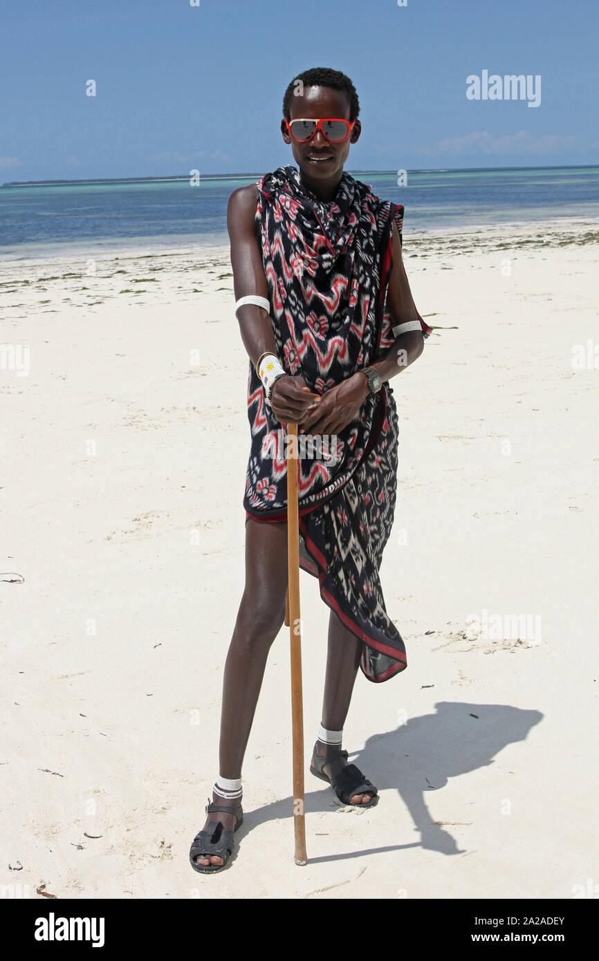 Maasai man with cane standing on the beach, Zanzibar, Unguja Island, Tanzania. Stock Photo