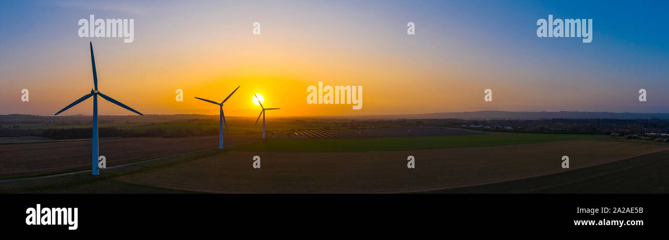 Three large wind turbines at sunrise taken from the air in panoramic ...