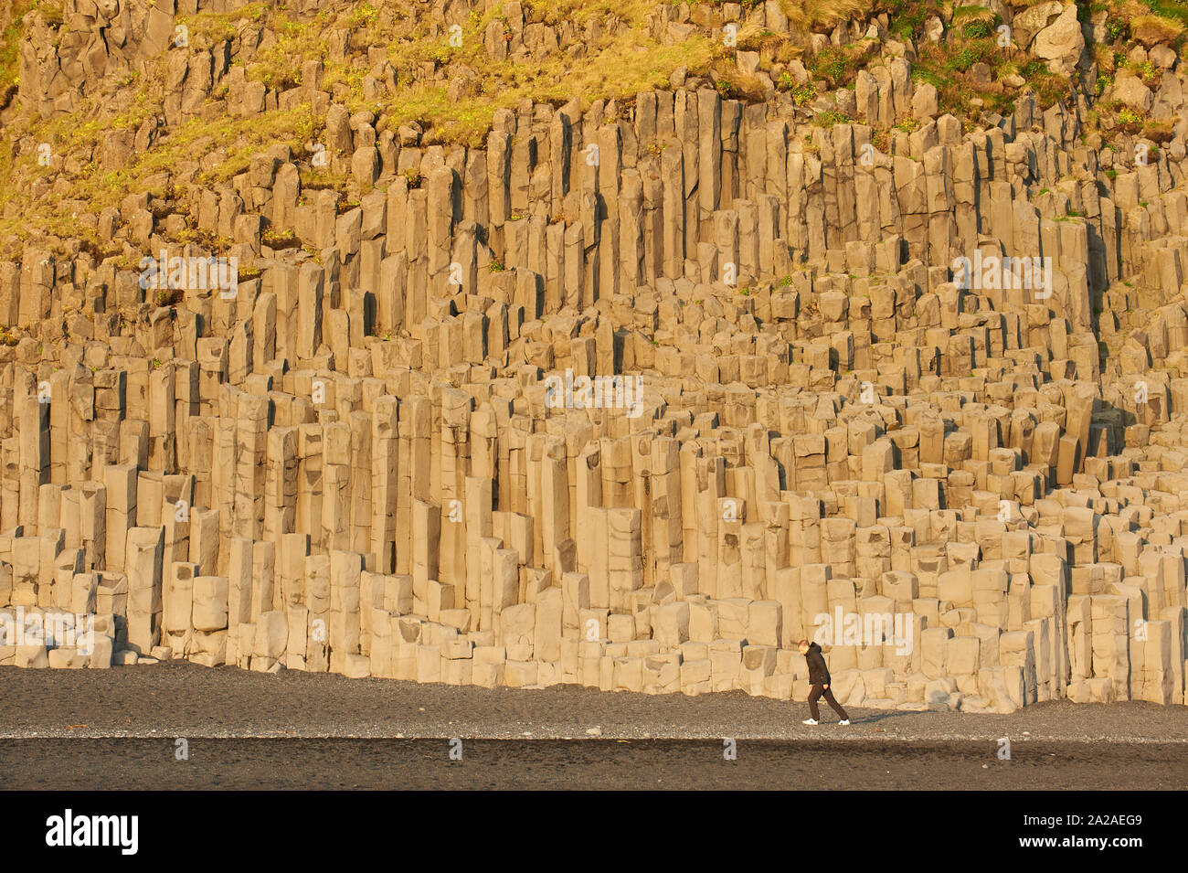 Basalt columns of Reynisfjara, person walking against strong wind on black beach Vik i Myrdal Southwest Iceland Stock Photo