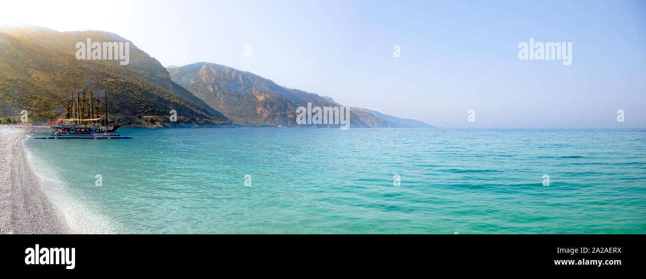 panoramic of sailing ship moored in a bay with calm seas and mountains