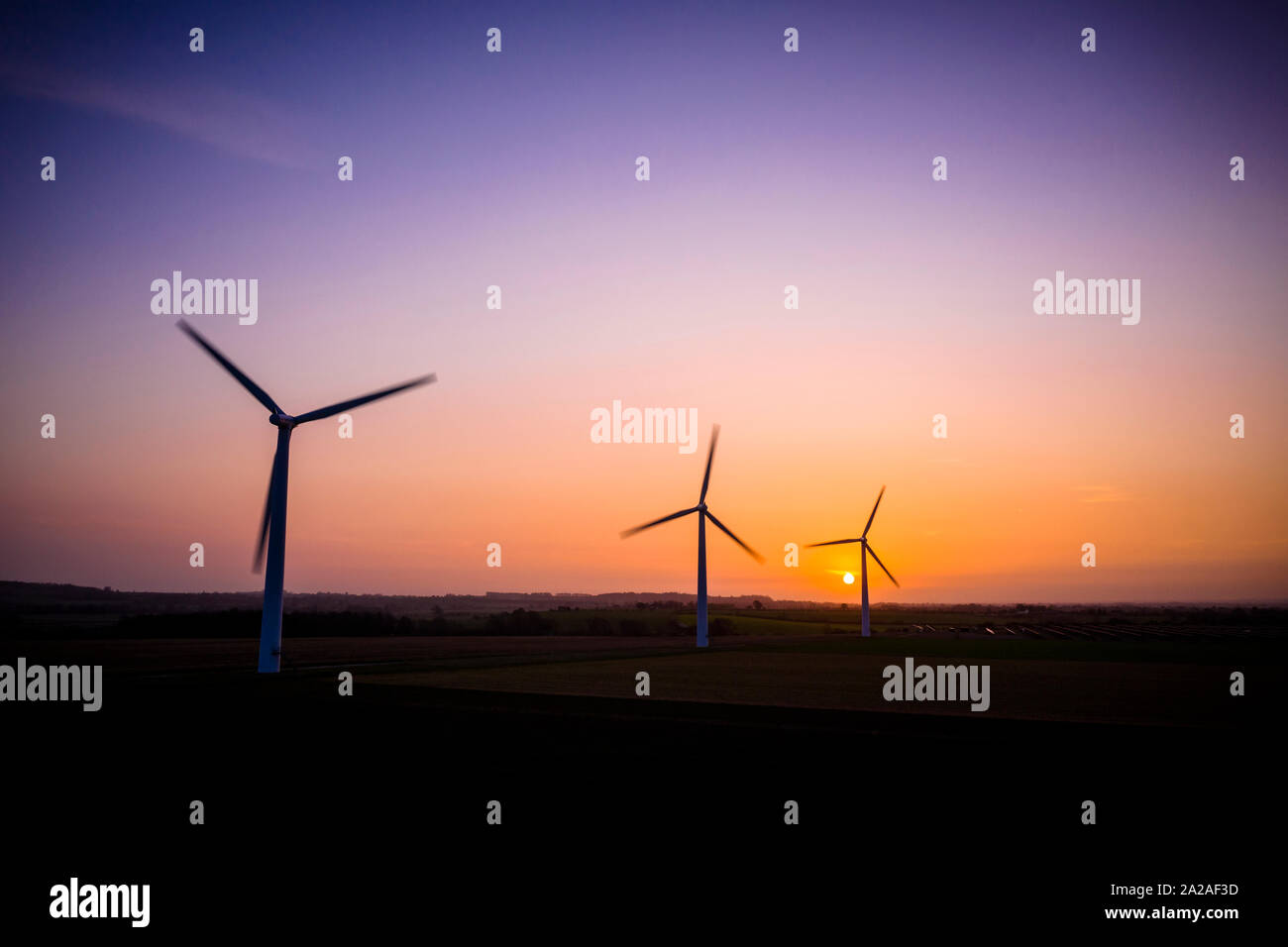 Three large wind turbines at sunrise taken from the air Stock Photo - Alamy