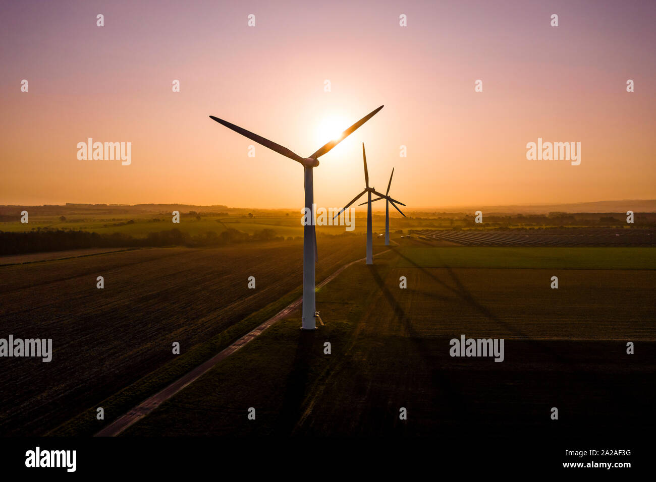 Three large wind turbines at sunrise taken from the air Stock Photo - Alamy