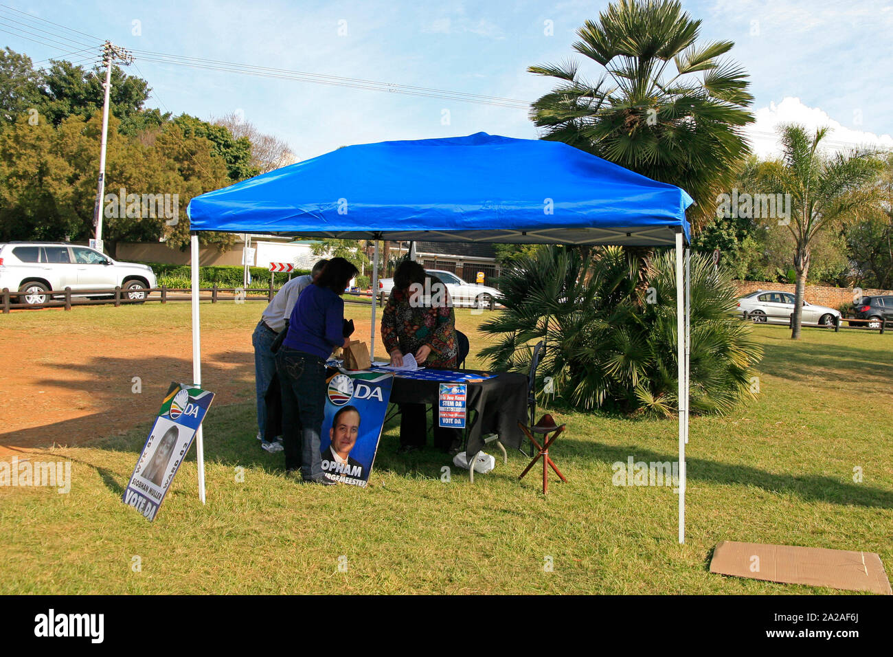 Democratic Alliance posters and people at voting booth on table in a park, Lynwood, IEC Pretoria voting station, Border road East, Lynwood, Pretoria, Gauteng Province, South Africa. Stock Photo