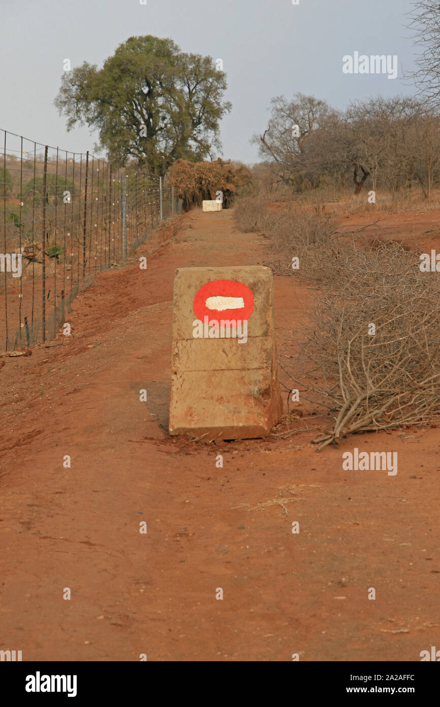 Fence and no entry sign, concrete block on dirt road in the bushveld, Marloth Park, bordering Kruger National Park. Stock Photo