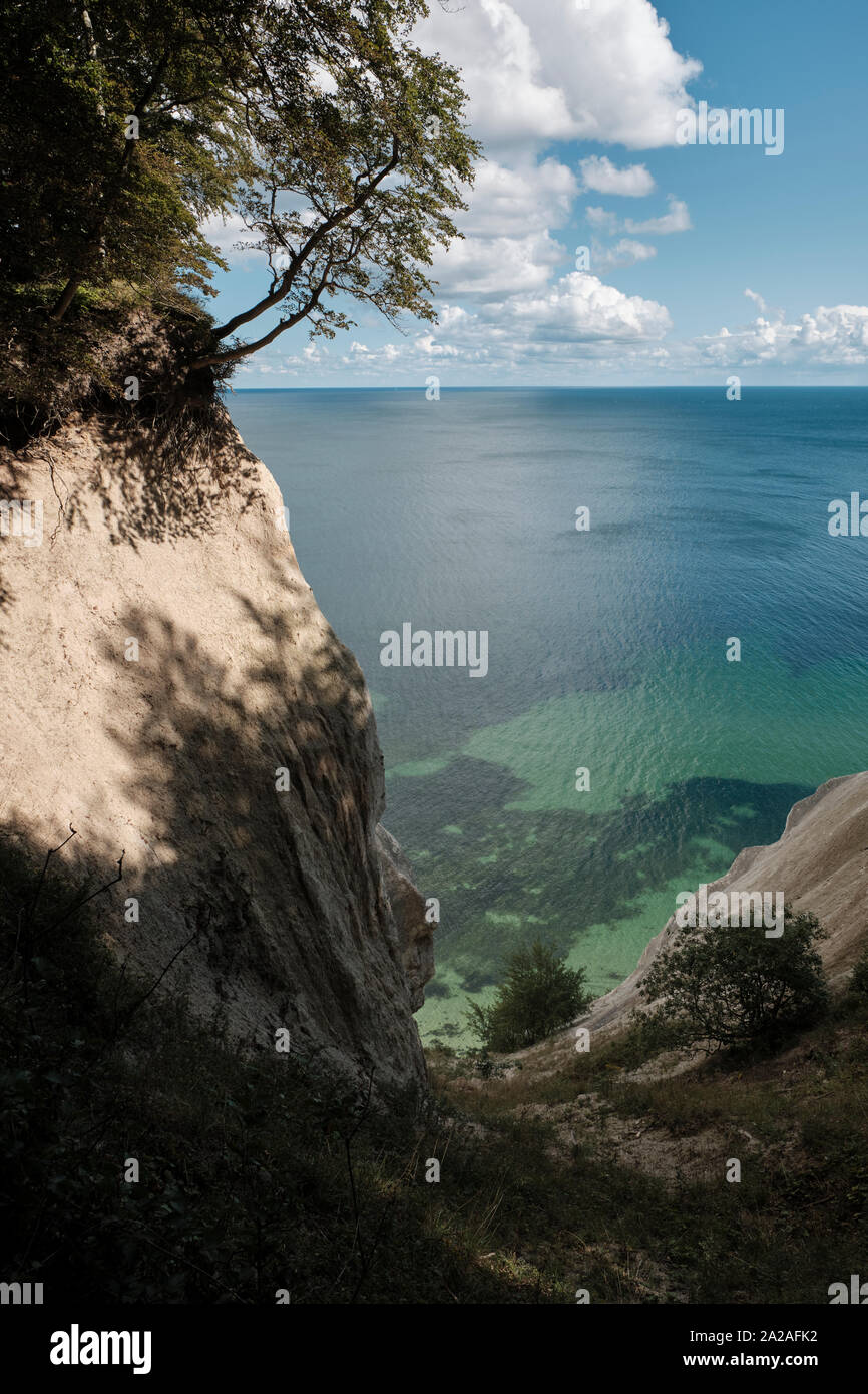 Romantic insight into a canyon of the Danish chalk cliffs on a sunny day with blue sky and white clouds on the horizon Stock Photo