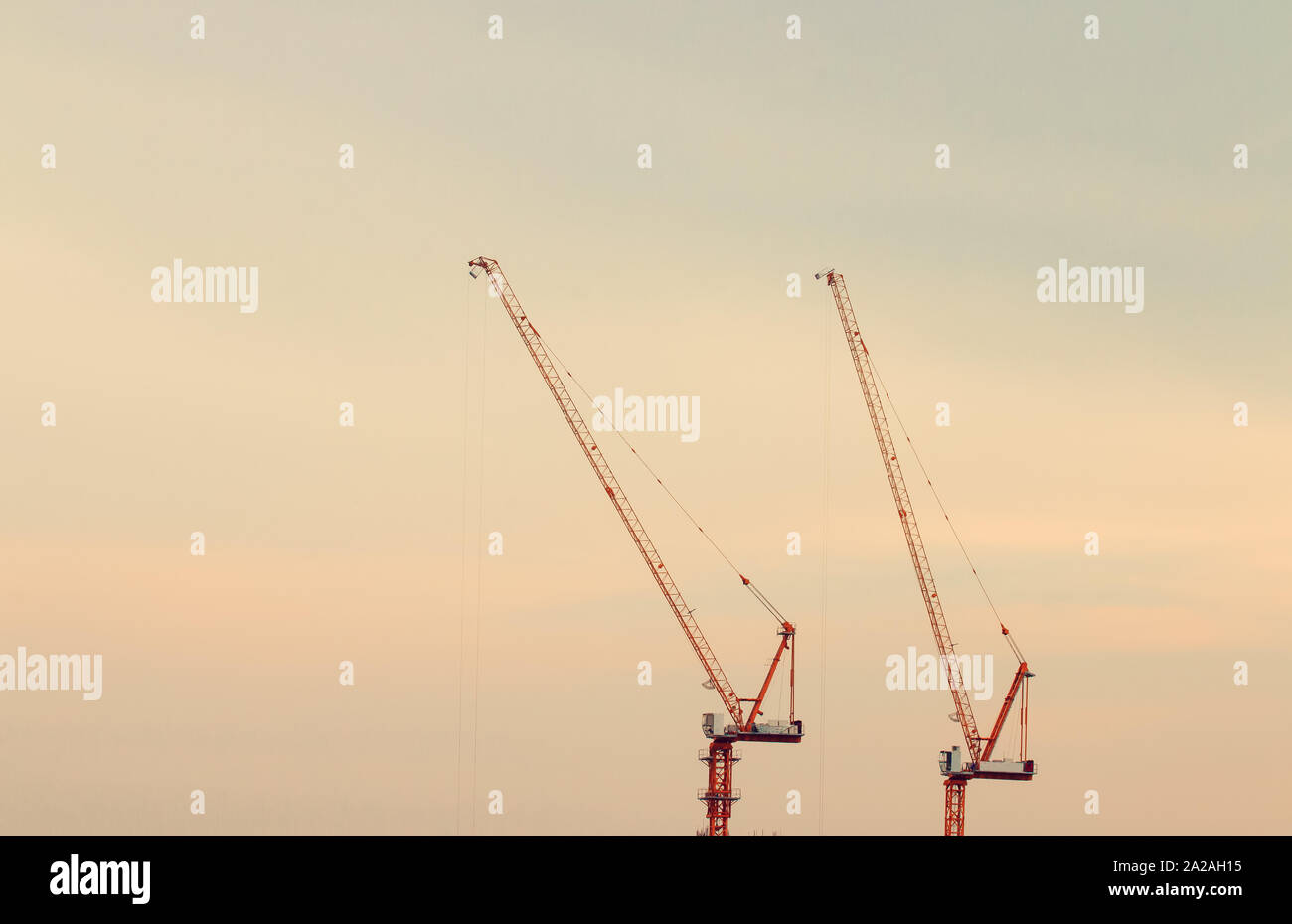 Construction cranes on the sunset sky background Stock Photo - Alamy