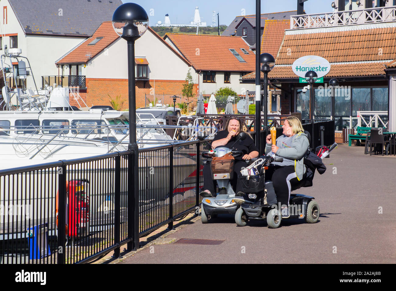 18 september 2019 Two overweight ladies eating and enjoying very large ice cream cones at the Port Solent Marina complex in Hampshire England Stock Photo