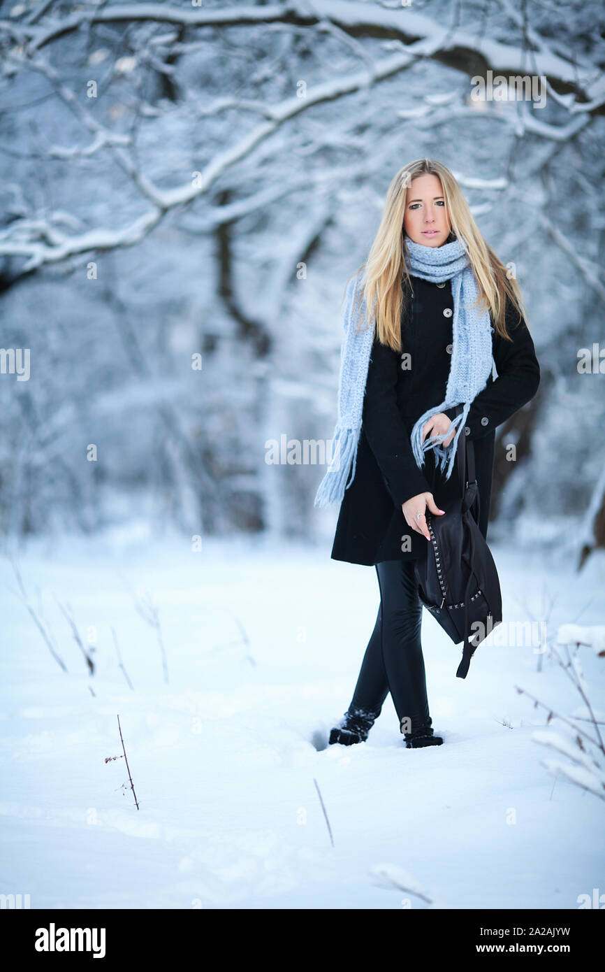 Attractive young blonde girl walking in winter forest. Pretty