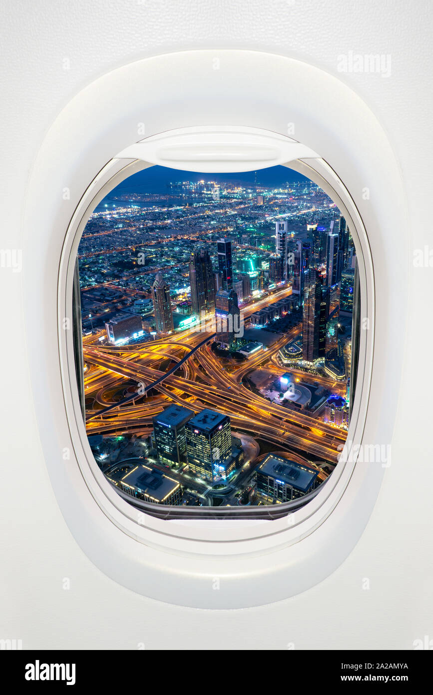 Dubai at night seen through the window of airplane, travel in UAE concept Stock Photo