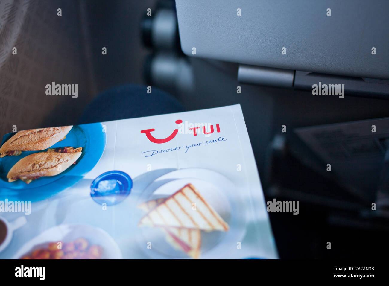 In-flight menu showing TUI brand on board a flight. Close-up of the branding within the cabin using natural light. Man holding the menu. Stock Photo