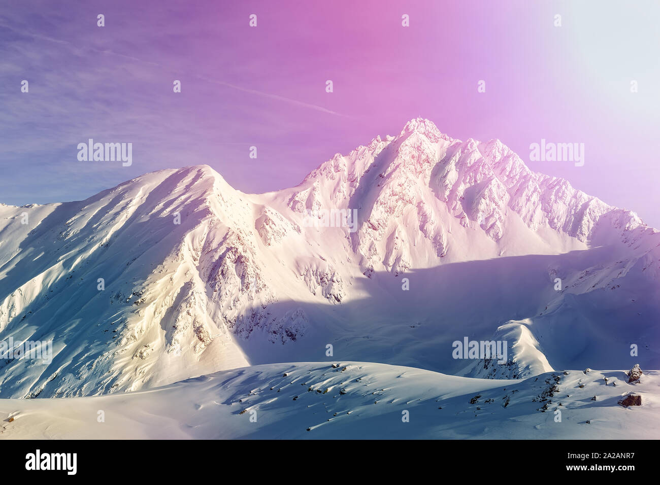 Dramatic scenic pink to purple sunrise in austrian alpine mountain peaks covered with snow layer in winter . Idyllic clear sky on background. Natural Stock Photo