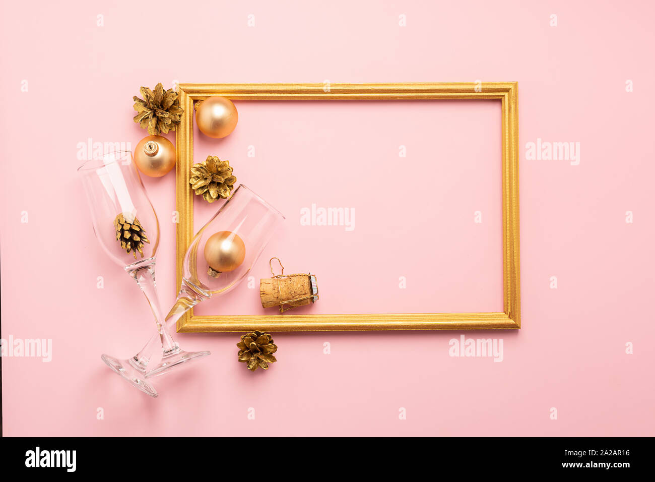 New Year or Christmas layout balls serpentine cork from a bottle of gold color empty wine glasses on a pink background. Holiday concept. Flat lay. Cop Stock Photo