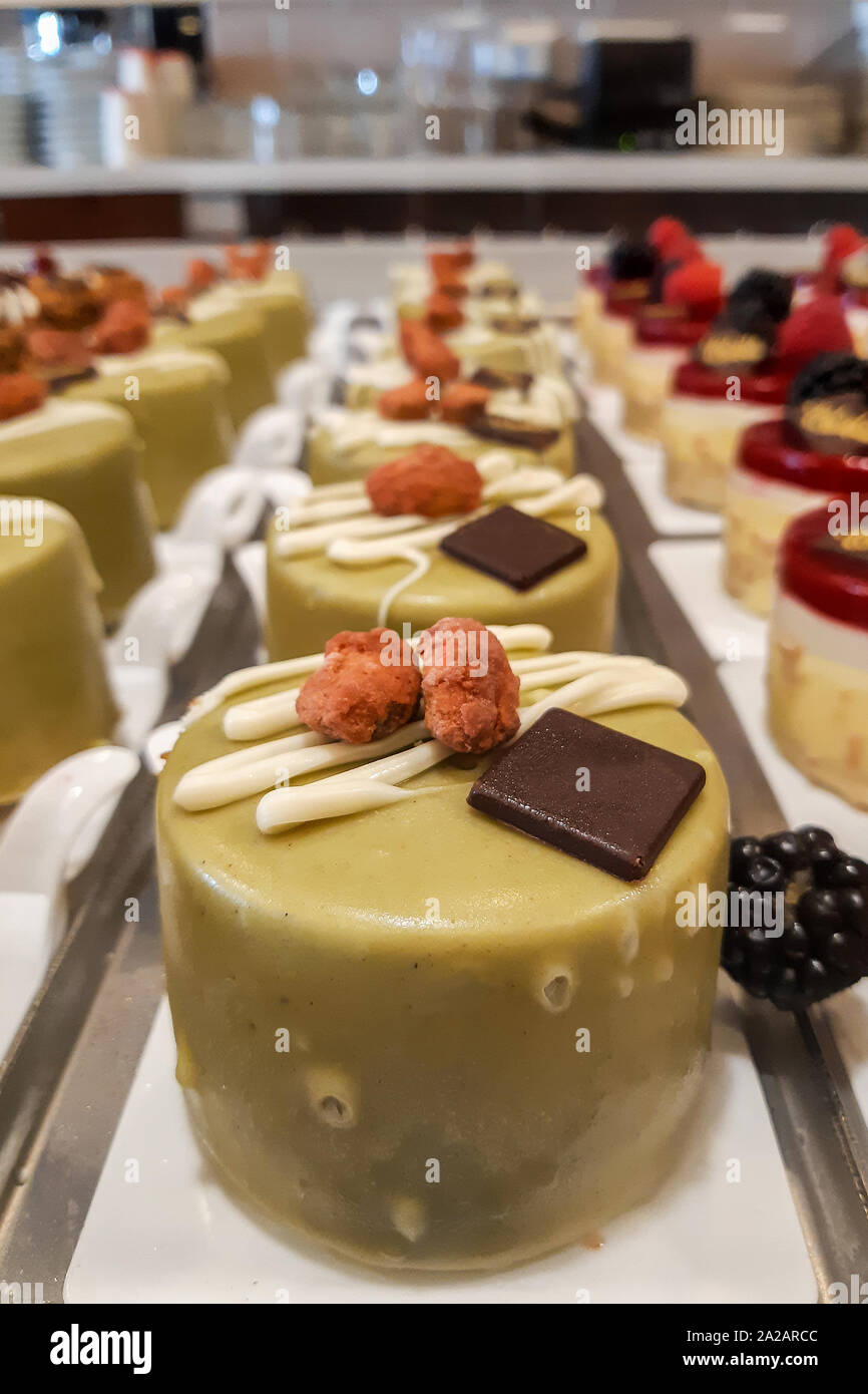 Glazed Pistachio green Cake decorated with yellow cream and Candied almonds with black chocolate Stock Photo