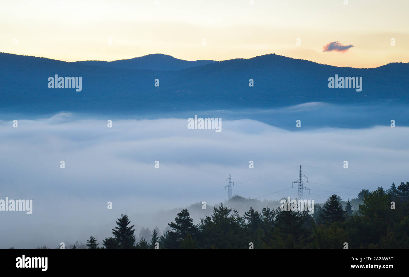 Gacka valley sunrise, transmission towers emerging from the fog Stock Photo