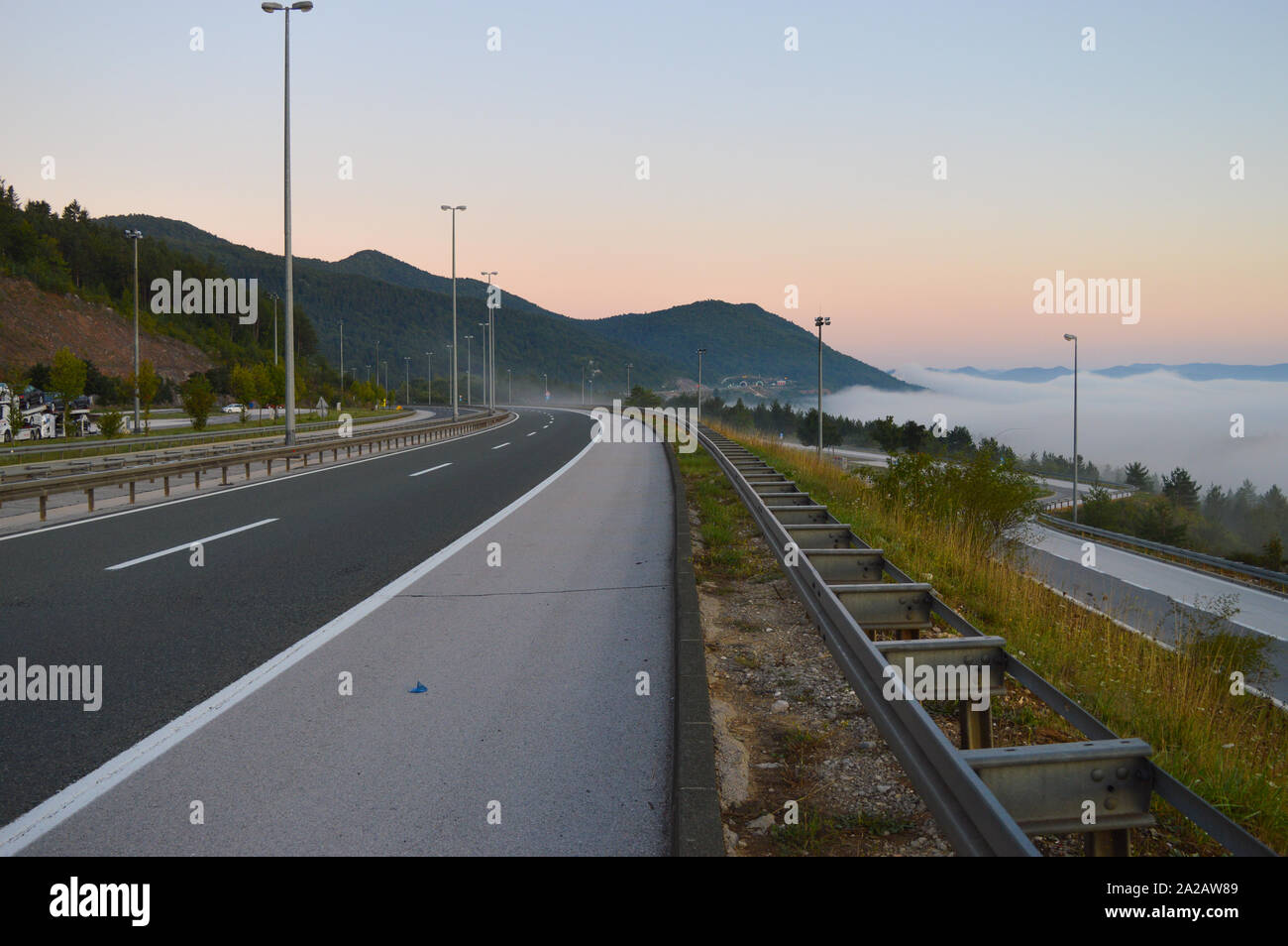 Empty highway at dawn, Gacka valley covered with mist, Croatia Stock Photo