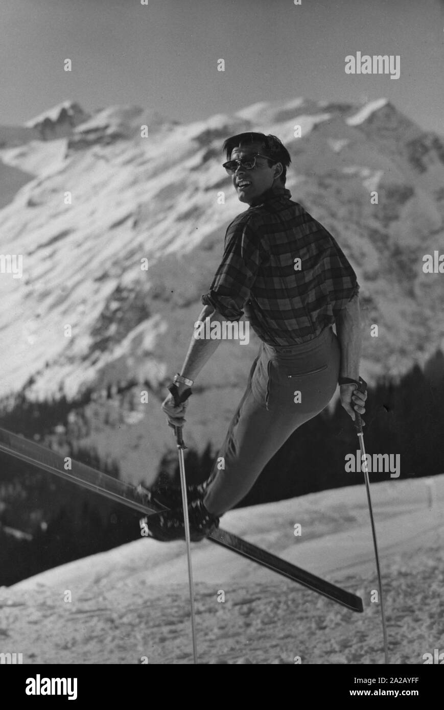 The Austrian skier Tony Sailer posing with skis and poles in front of the snow-covered Alps. Stock Photo