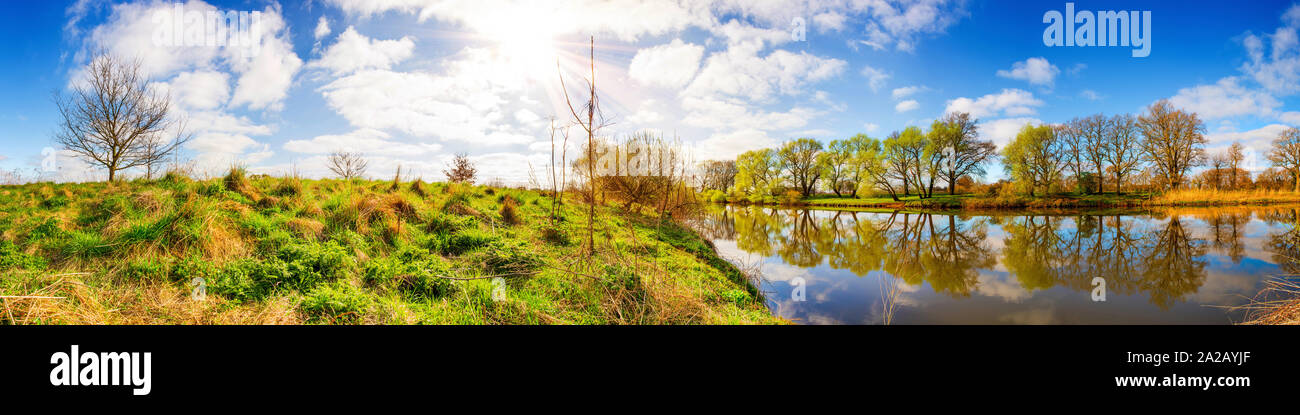 Panorama einer Landschaft mit Sonne, Fluss und Wiesen Stock Photo