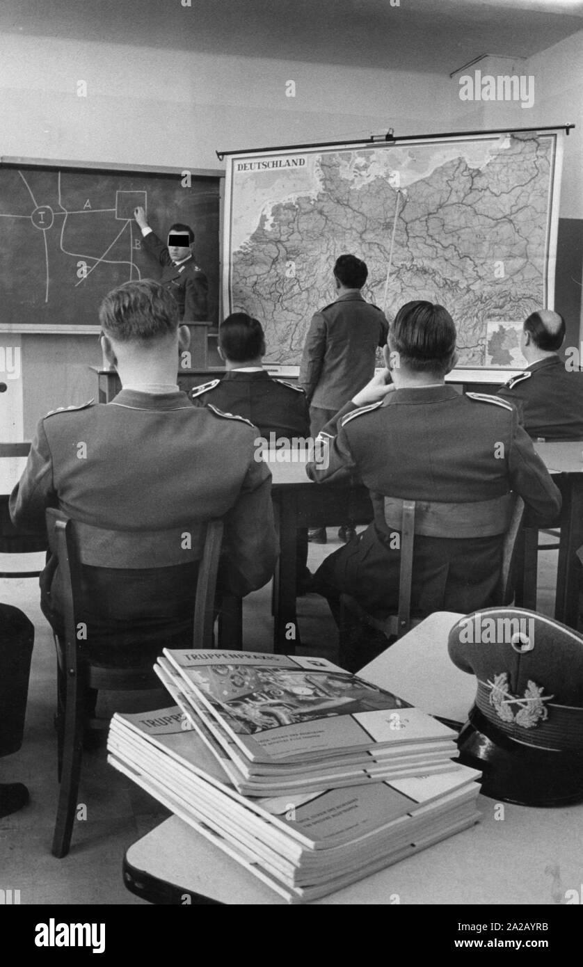 In the Defence School sergeants and senior officers are sitting together in the classroom. The instructor explains something with a schematic representation on the board. A trainee points to the northern border region of the German-Polish border. In the foreground: a pile of the magazine 'Truppenpraxis'. Stock Photo