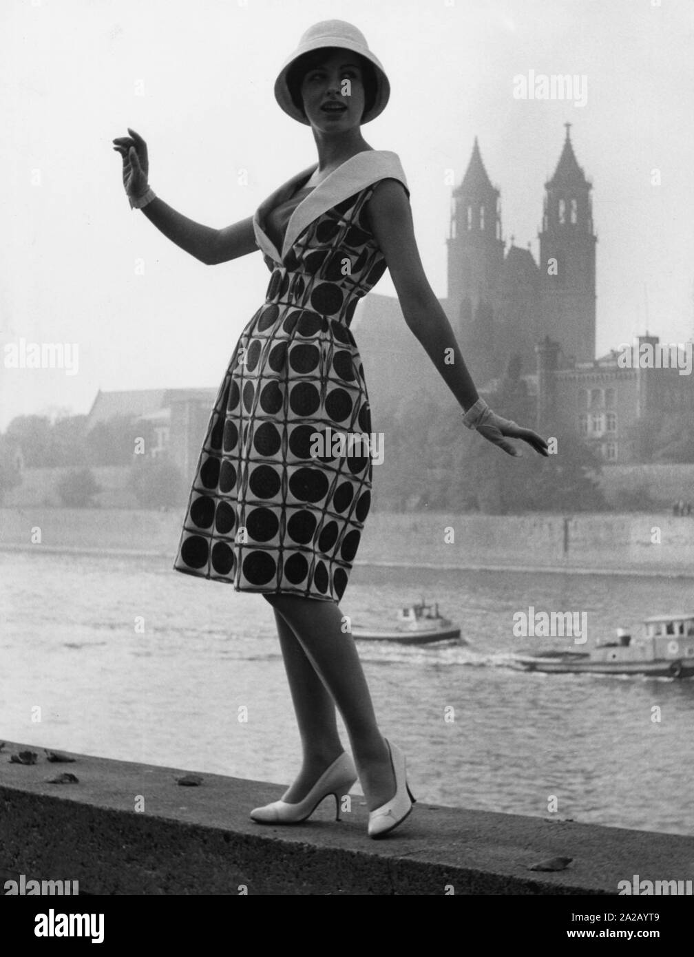 Model Evelyn posing on the banks of the Elbe in casual clothing. She wears a patterned dress with white shoes, gloves and hat, designed by the fashion designer Heinz Bormann from Magdeburg. Stock Photo