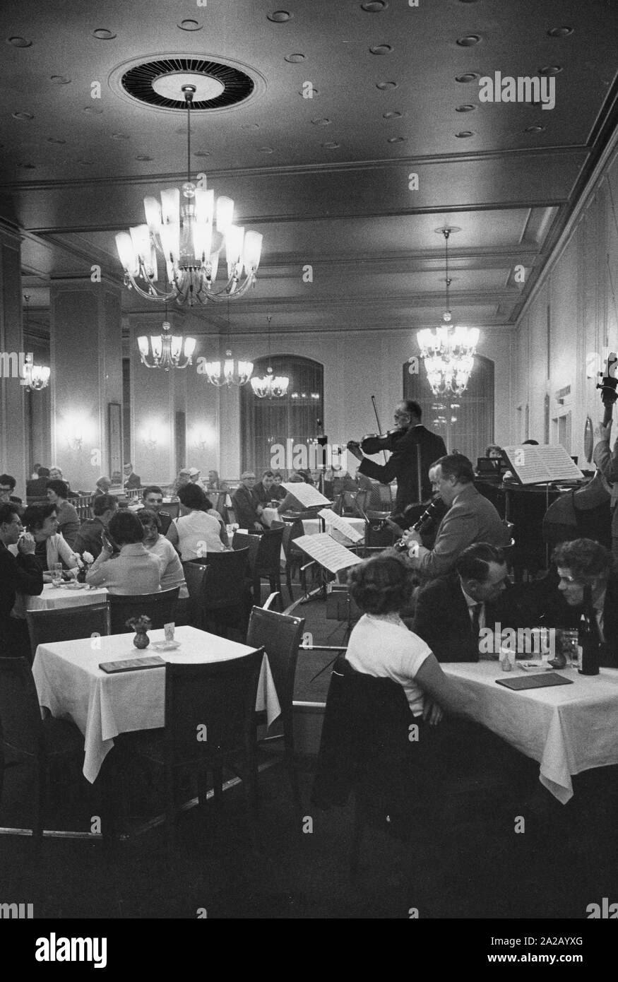 A dance event is taking place in a festive hall. Here: musicians (piano, clarinet, violin, double bass), guests sitting at tables. Stock Photo